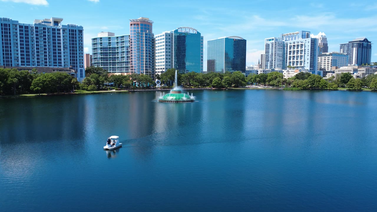 Lake Eola swan paddle boat crossing the foreground with the green-domed fountain spraying mid-lake